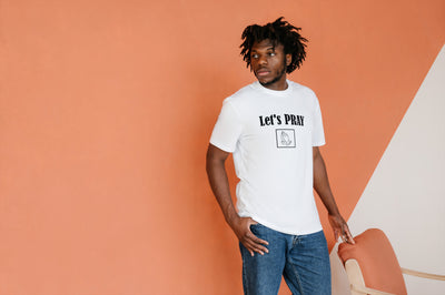 Let's Pray Men T-shirt. T-shirt shows words in black and image of praying hands in a square shape. T-shirt shown in white.